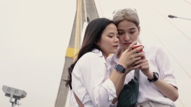 Asian Lesbian Couples Using Smartphones Browsing Website While Standing Bridge — Stock Video