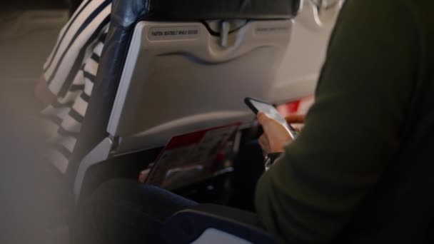 飛行機の中でスマートフォンを使ってアジア人の男を閉じます 旅行休暇の時間概念 — ストック動画