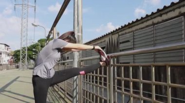 Sporcu genç Asyalı kadın koşmadan önce ısınıyor ve ısınıyor ve kulaklık takıyor. Şehirde müzik dinliyor. Sağlıklı yaşam tarzı.