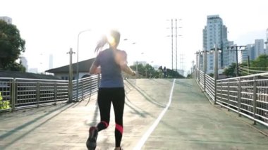 Şehirdeki sokakta koşan genç bir Asyalı bayan sporcu. Günbatımında sokakta kardiyo antrenmanı yaşam tarzı. Sağlıklı yaşam tarzı.