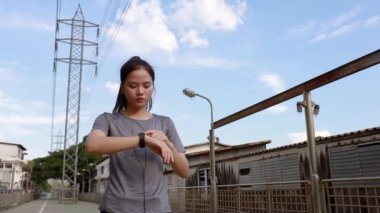 Güzel bir Asyalı genç bayan atlet, akıllı bir kalp atışına bakıyor. Gün batımında sokakta koşu yaşam tarzı. Sağlıklı yaşam tarzı.