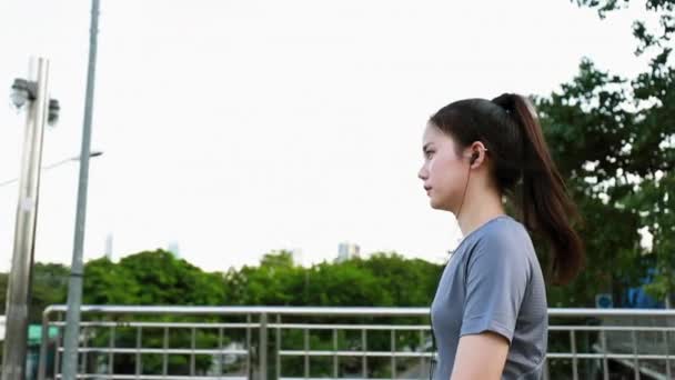 ランニング後に歩くアジア系の若い女性アスリートの姿を追いかける 日没時に路上でワークアウトのライフスタイルをジョギング 健康的なライフスタイル — ストック動画