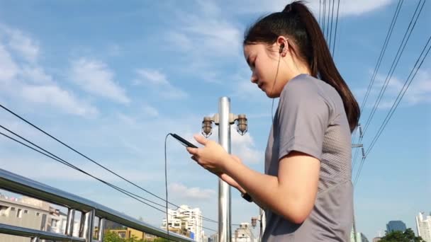 迷人的亚洲女运动员跑步后用智能手机检查心率 日落时在街上慢跑锻炼生活方式 健康的生活方式 — 图库视频影像