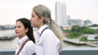 Mutlu Asyalı lezbiyen çift Tayland 'da Rama VIII Köprüsü' nde yürüyor ve tatilde eğleniyor. LGBT kavramı.