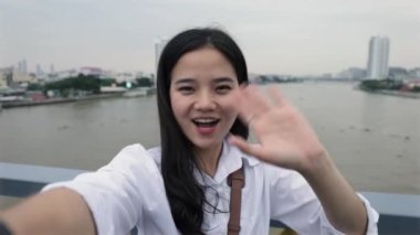 Tayland 'da Rama VIII Köprüsü' nde durup tatilde eğlenirken arkadaşlarıyla sohbet eden genç ve güzel bir Asyalı kadın..