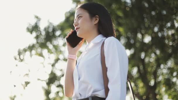 身穿白衬衫的美丽的亚洲女商人正在公园外面用智能手机发短信 在社交媒体上分享信息 — 图库视频影像