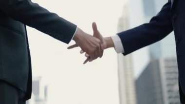 Asyalı iş kadını ve işadamı, büyük bir ofis binasının yakınında dikilirken ortaklık anlaşması yapıyor..