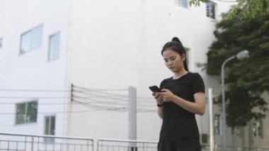 Genç Asyalı bayan sporcu, spor yaptıktan sonra akıllı telefon kullanarak koşuyor mesajları sosyal medyada paylaşıyor..