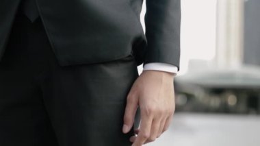 Kapalı cepli Asyalı iş adamı takım elbiseli şehir caddesinde duruyor..