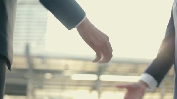アジアのビジネスマンやビジネスマンが握手を交わしながらビジネスを取引午前中に大きなオフィスビルの都市の近くの通りの外に立っている — ストック動画