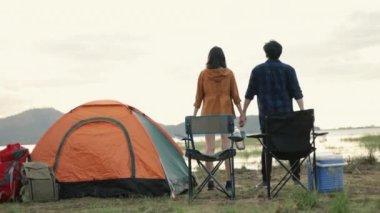 Genç Asyalı çift tezahürat yapıyor ve başarılı tırmanışlarını kutluyor kampa güzel bir günbatımında kollarını kaldırarak tırmanıyorlar..