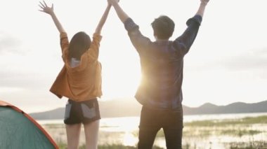 Genç Asyalı kampçılar, dağlarda yürüyüş yaparak başarılı tırmanışlarını kutluyor güneşli, güzel bir manzara üzerinde kamp kuruyor tatil yolculuğunun tadını çıkarıyor..