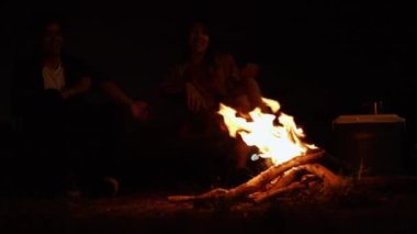 Asyalı çiftlerin siluetleri kamp ateşinde oturuyor ve yaz tatillerinde eğleniyorlar.. 