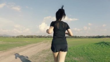 Kırsal bir yolda koşan Asyalı kadını takip et. Dağ manzaralı güzel gün batımı, spor koşusu konsepti..