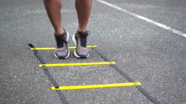 Çevik merdiven teçhizatıyla yakın plan bacak sporcusu eğitimi. Kamu parkı konseptinde sporcu eğitimi..