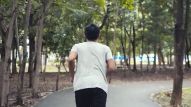 Parkta koşan yakışıklı Asyalı adam. Sporcu egzersiz sağlıklı açık hava konsepti.