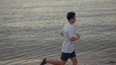 Yakışıklı bir Asyalı sporcu yazın plajda egzersiz yapıyor. Sağlıklı spor yaşam tarzı konsepti.