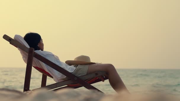 若いアジアの女性は海の景色を見てリラックスしたビーチのデッキチェアに横たわっている感じ 休暇夏のコンセプト — ストック動画