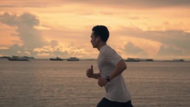 Yakışıklı bir Asyalı sporcu yazın güzel altın gökyüzü boyunca kumsalda egzersiz yapıyor. Sağlıklı spor yaşam tarzı konsepti.