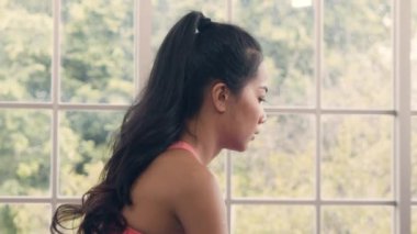 Spor kıyafetli Asyalı kadın, evde oturma odasında çocuk pozu yoga egzersizi yapıyor..