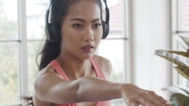 Spor kıyafetli, kulaklık takan, yoga egzersizi yaparken müzik dinleyen güzel bir Asyalı kadın..