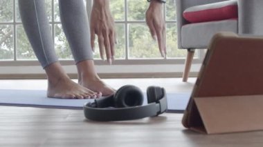 Spor kıyafetli güzel Asyalı kadını kapat. Karantina sırasında evdeki bir paspasın üzerinde yoga egzersizi yapıyor..