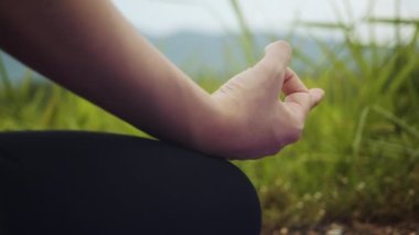 Eller, genç Asyalı kadının güneş doğarken dağlarda ruhani yoga pozu vererek yoga egzersizi yapmasını engelliyor. Sağlık ve Sıhhat kavramı.