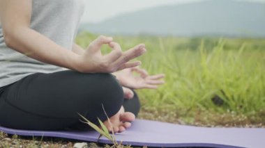 Meditasyonda oturan güzel Asyalı kız güneş doğarken güzel dağların manzarasında yoga pozisyonunda pranayama dengesi kuruyor. Sağlık ve Sıhhat kavramı.