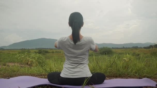 瞑想のポーズで座っている美しいアジアの女性は 日の出の間に美しい山の景色の中で薬ヨガのプラナヤマバランスをポーズ 健康とウェルネスの概念 — ストック動画