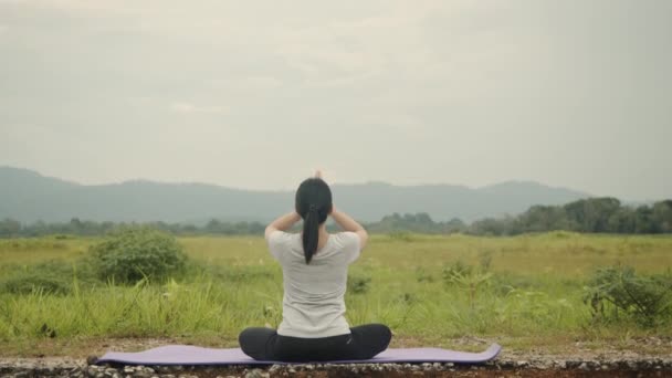 美しいアジア系白人女性が瞑想に座っていると 午前中に美しい山の景色の中でヨガのプラナヤマバランスをポーズします 健康とウェルネスの概念 — ストック動画
