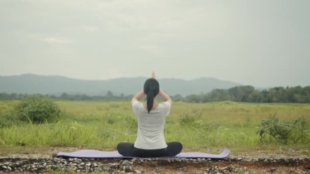瞑想に座っている美しい白人女性は 午前中に美しい山の景色の中でヨガのプラナヤマバランスをポーズします 健康とウェルネスの概念 — ストック動画