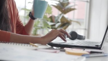 Bilgisayarı ve akıllı telefonu kullanan bir iş kadınının ofiste otururken kahve içerken fotoğrafını çek..