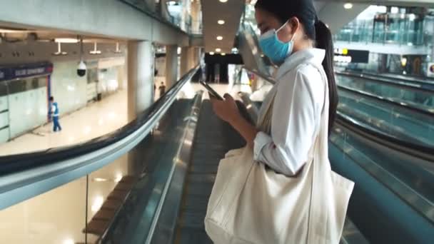 Turistas Asiáticas Usan Máscara Quirúrgica Teléfonos Inteligentes Escaleras Mecánicas Terminal — Vídeo de stock