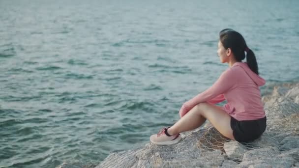Молодая Бегунья Сидящая Камнях Отдыхает Любуясь Закатом Пляже — стоковое видео