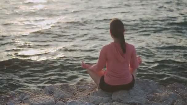 Asijské krásné dívka sportovní dívka trénink meditace sedí na kameny u moře během západu slunce. Zen jóga meditace praxe v přírodě.