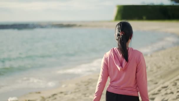 日出时分 女运动员在海滩上散步 穿着运动服的女赛跑选手跑步后休息一下 健康生活方式概念 — 图库视频影像