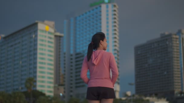 Atrakcyjna Azjatka Biegacz Patrzy Morze Stojąc Plaży Mając Tle Budynku — Wideo stockowe