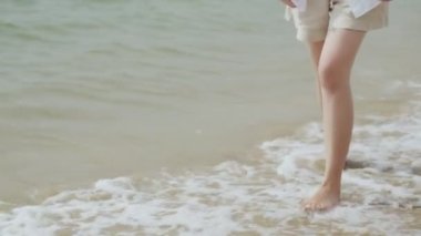 Tatil haftasonunda kumsalda yürüyen beyaz kadın mutluluğu, deniz manzarasında neşeli mutlu bir yolculuk yapan Asyalı kadın. Yakın çekim..