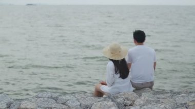 Erkek ve kadın çift sahilde bir taşın üzerinde oturup tatilin tadını çıkarıyorlar. Mutlu bir yaz geçiriyorlar. Konuşuyorlar, gülüyorlar ve akşamları sahildeki manzaraya bakıyorlar..