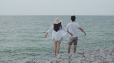 Aşık Asyalı çift hafta sonu tatilinde kollarını havaya kaldırarak başarıyı kutluyor. Plaj gezisinde romantik bir çift..
