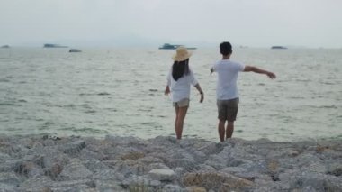 Aşık Asyalı çift hafta sonu tatilinde kollarını havaya kaldırarak başarıyı kutluyor. Plaj gezisinde romantik bir çift..