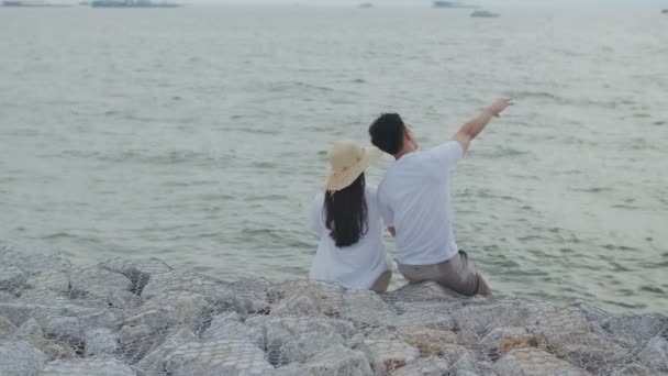 男性と女性のカップルは 夏休みの幸せな話と笑いを楽しんで 日没時にビーチの景色を見てください — ストック動画