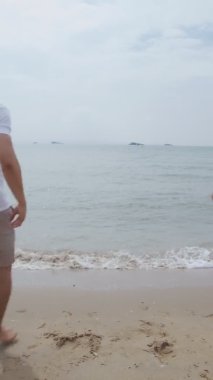 Dikey Video: Asyalı aşık çift koşuyor ve tatilde kollarını havaya kaldırarak başarıyı kutluyor.