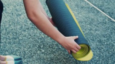 Parktaki yoga sınıfındaki Asyalı kadın yoga minderini kapat..