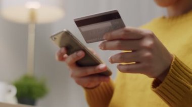 Çekici bir Asyalı kadının cep telefonunu online alışveriş için kullanışının yakın çekimi. Kredi kartı tutan ve evde akıllı telefon kullanan bir kadın. Çevrimiçi alışveriş, internet bankacılığı, ödeme e-ticaret.
