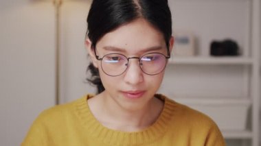 İnternette araştırma yapan ve COVID-19 salgını sırasında internetten alışveriş yapan gözlüklü Asyalı kadın evde kalıyor..