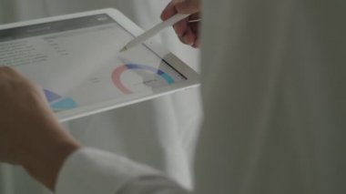 Kapalı çekim işadamı tableti tutuyor ve tablet tablet tablosu tablosu istatistik verilerini kullanarak ofiste rapor veriyor..