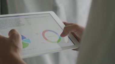 Tablet kullanan, mali raporları inceleyen ve iş büyümesini analiz eden yakın plan iş adamı.