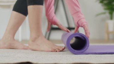 Spor salonu bittikten ya da evde yoga yaptıktan sonra beyaz kadın paspasların ellerini kapat..