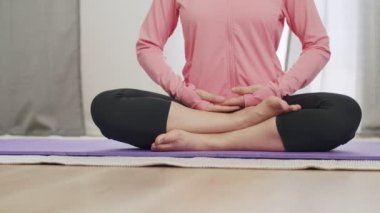 Yakın plan güzel Asyalı kadın COVID-19 salgını sırasında evde lotus pozisyonunda meditasyon yapıyor..